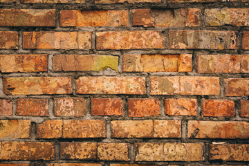 Old grungy brick wall. Free space for an inscription. Can be used as a background or poster. Fragment of a wall with bumps and shabby plaster.