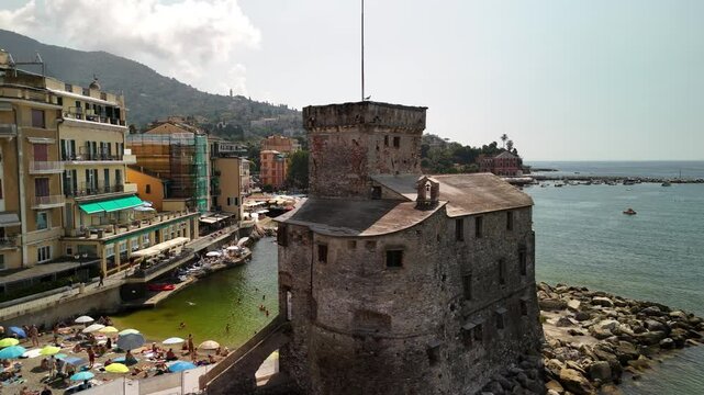 A sunny day in Rapallo showcasing colorful umbrellas and a historic tower by the sea