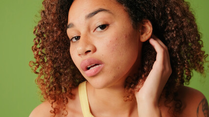 Nice girl touching her face skin. Confident body positive teenager looks at the mirror and touches...