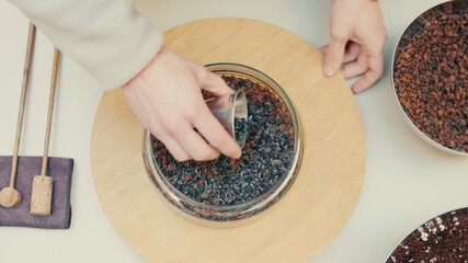 Top view of the man's hands prepearing soil for a terrarium with a house plants, Close-up