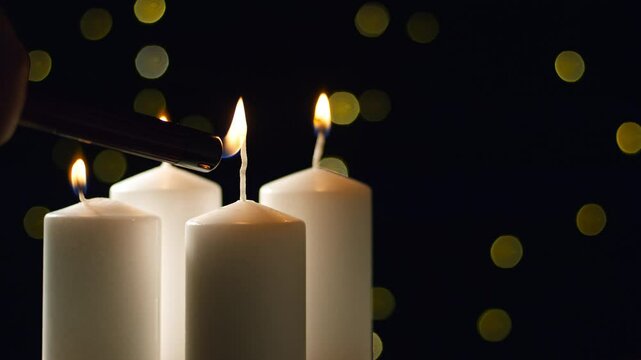 Hand lightning the last fourth Advent candle on Christmas Eve, a festive backdrop, close-up shot. Hope, purity, love, and spirit concepts.