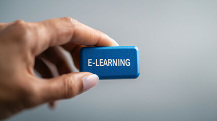 Fototapeta premium E-learning is modern educational approach that enhances learning experiences. This showcases hand holding vibrant blue block labeled E LEARNING, symbolizing digital education