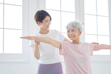高齢者の女性にヨガを教えるインストラクター