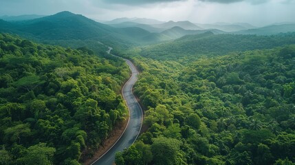 A drone shot capturing a winding mountain road surrounded by lush forests