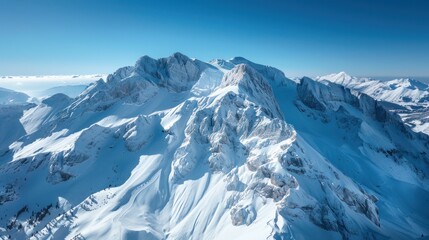 Obraz premium A drone perspective of a snowy mountain range with clear blue skies,