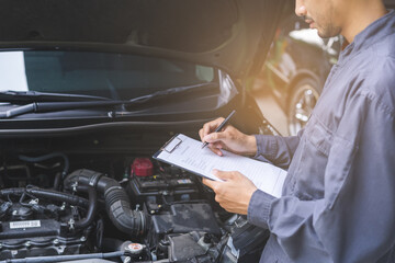 Auto check, car service shop concept. Automobile repairman writing job checklist on clipboard, mechanic checking engine to estimate repair machine, inspecting maintenance by engineer at vehicle garage