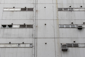 Old building with multiple windows, ventilators and pipe. Exterior of an old commercial building in...