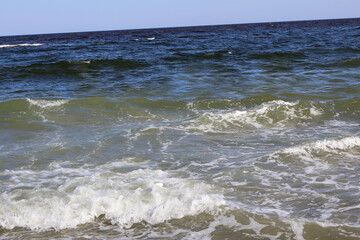 Dynamic Ocean Waves Crashing onto the Shore Under a Clear Blue Sky