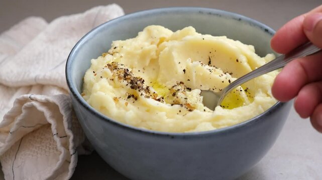 Mashed potatoes with butter and pepper in a blue bowl.