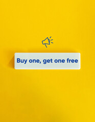 Buy One, Get One Free. Deal, Promotional Offer, Campaign, Sale. Megaphone Icon and Blue Text on Block Letter Tile on Yellow Background. Minimal Aesthetic.