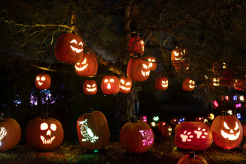 A dark and stormy Halloween night with numerous glowing jack-o'-lanterns scattered across the...