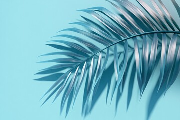 Obraz premium A close-up view of a shiny palm leaf against a serene blue background, highlighting its intricate textures and natural beauty.