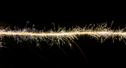 Line of christmas sparklers light trail on black background