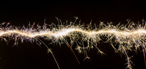Line of christmas sparklers light trail on black background