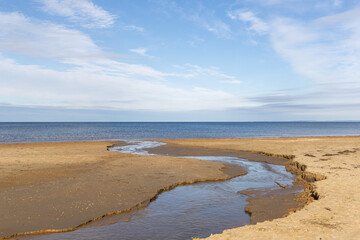 Flowing water outlet on empty beach with sea horizon