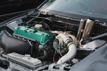 Close-up view of modified car engine, vibrant green valve cover, turbocharger, and intricate piping...