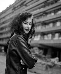 Smiling alternative woman looking at camera in front of building.