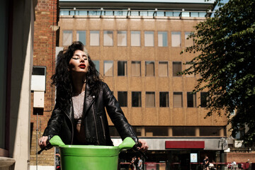 Alternative female model riding an electric bike in London.