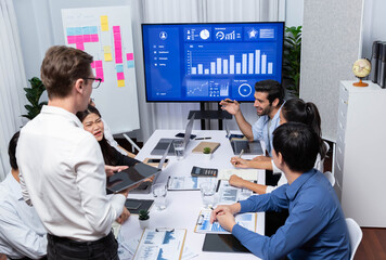 Analyst team utilizing BI Fintech to analyze financial data at table in meeting room. Businesspeople analyzing BI dashboard power for business insight and strategic marketing planning. Prudent