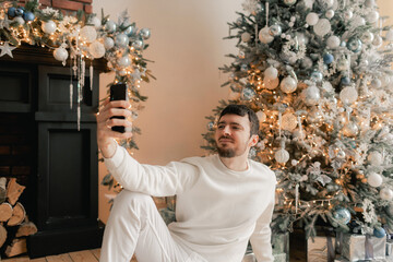 Happy man using smart phone home alone celebrating virtual Christmas video calling family and...