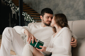 Young woman hugs her beloved husband giving him a gift on this special day. Concept of gifts for...
