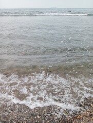 Portrait of waves, sand and small rocks on the beach