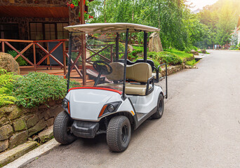 A white golf cart is parked on the street.