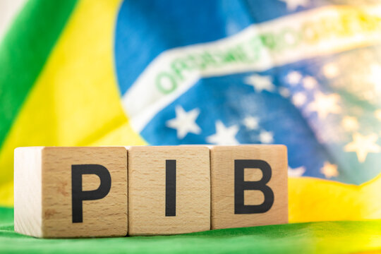 The word PIB (Gross Domestic Product) written on wooden cubes standing on the national flag of Brazil. Brazilian Portuguese language