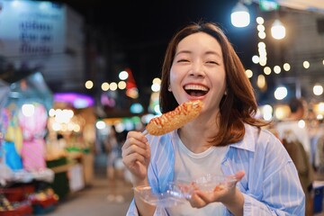 Happy Asian woman eating street food at local market.