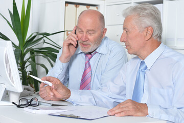 Two old business men sitting at desk and working