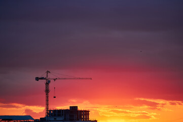 Fototapeta premium Construction Crane Silhouette Against Fiery Sunset