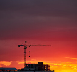 Crane and Buildings Silhouetted Against a Vibrant Sunset