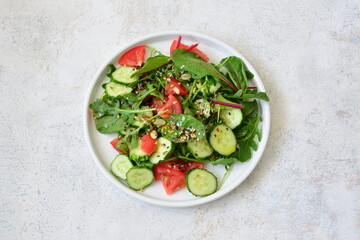 a plate of salad with cucumber, avocado and tomatoes and seeds top view 