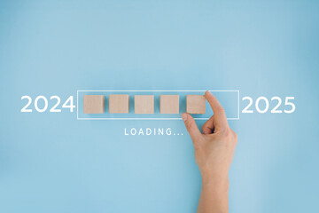 2025 New Year Loading. Female hand moving wooden blocks with Loading bar between 2024 and 2025 on a...