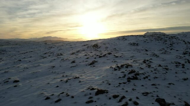 Aerial footage of a snow-covered terrain at sunset in in Drumrunie, North of Ullapool, Scotland, UK