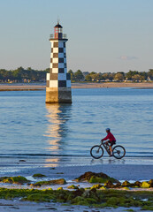 active senior woman cycling with her electric mountain bike along the beach of Loctudy in front of...