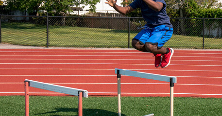 Athlete Jumping Over Hurdles on a Sunny Day at a Track and Field Facility