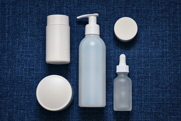 A composition of cosmetics in white packaging on a navy blue (denim) background