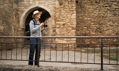 A retired male tourist takes photos while walking in an ancient fortress