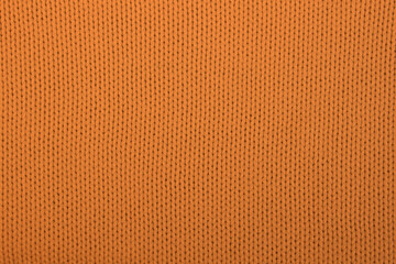 Soft light natural texture of knitted wool textile material background. Orange crochet cotton fabric woven canvas