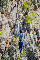 A tightrope walker walks along a cable stretched over a canyon.