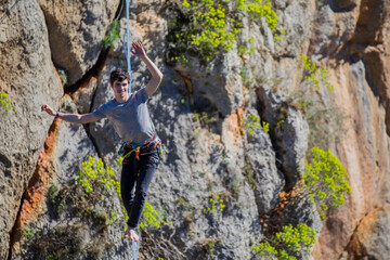 A tightrope walker walks along a cable stretched over a canyon.