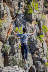 A tightrope walker walks along a cable stretched over a canyon.