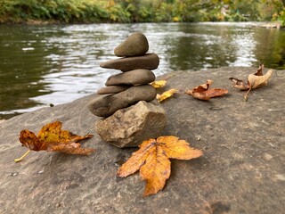 Balancepyramide am Fluss mit Laub im Herbst 