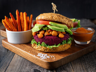 A gourmet vegan burger adorned with colorful vegetables and a rich dip, elegantly displayed on a wooden surface ai.