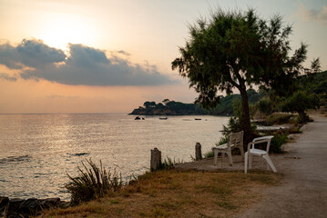 White chairs at the seashore in Zakynthos to relax in tranquility during the golden hour. A serene spot by the sea, perfect for a peaceful moment.