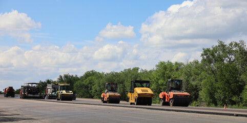 A group of construction vehicles are lined up on a road