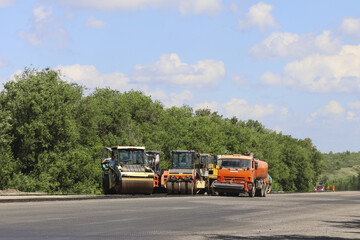 A group of construction vehicles are parked on the side of a road