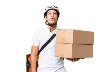 Delivery man wearing a helmet bike over isolated background looking up and with surprised expression