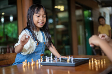 Fototapeta premium A young girl is playing a game of chess with another child